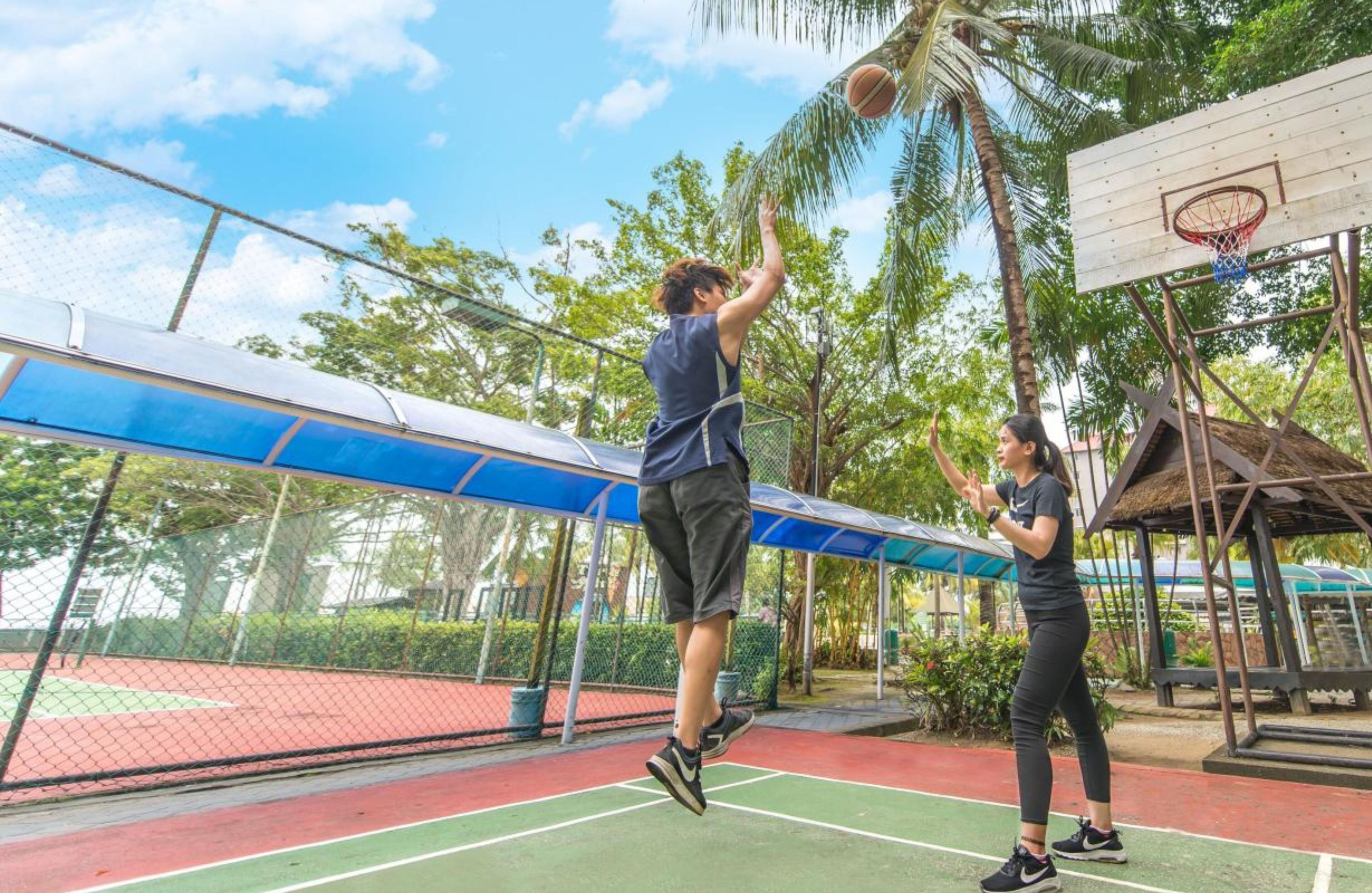 A basketball court with a net, a basketball hoop, and a person jumping to shoot.