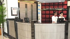 A reception desk at Glory Beach Resort with a modern design, featuring a curved layout and a red accent wall.