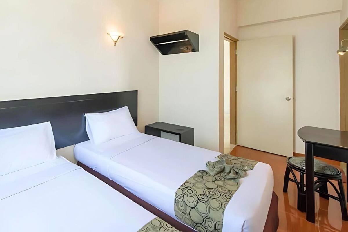 A hotel room with two beds, a desk, and a chair.