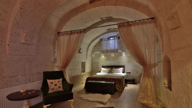 Quarto com uma cama, uma cadeira, um tapete de pele e uma mala.
