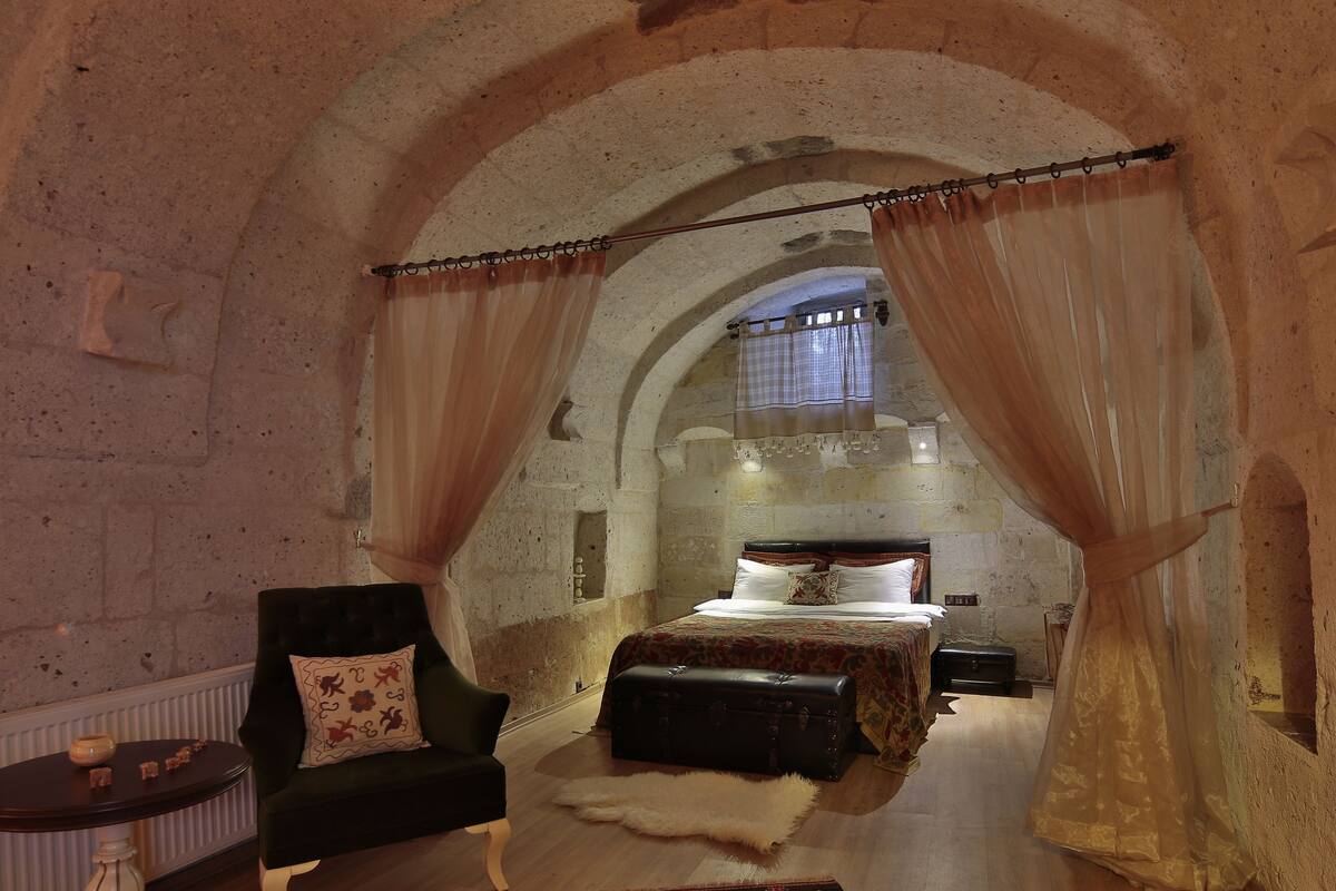A room with a bed, a chair, a fur rug, and a suitcase.