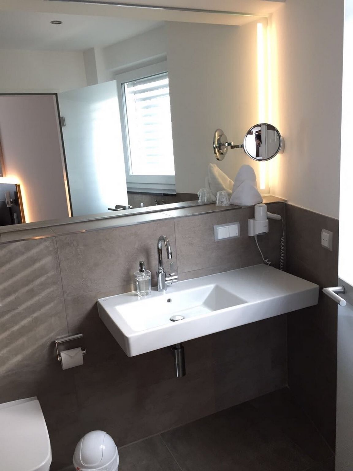 Un baño moderno con un lavamanos grande, un espejo y un inodoro.