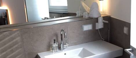 Un baño moderno con un lavamanos grande, un espejo y un inodoro.