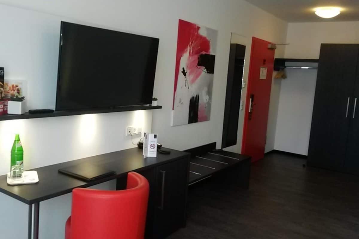 A modern kitchen with a flat-screen TV, a red chair, and a dining table.