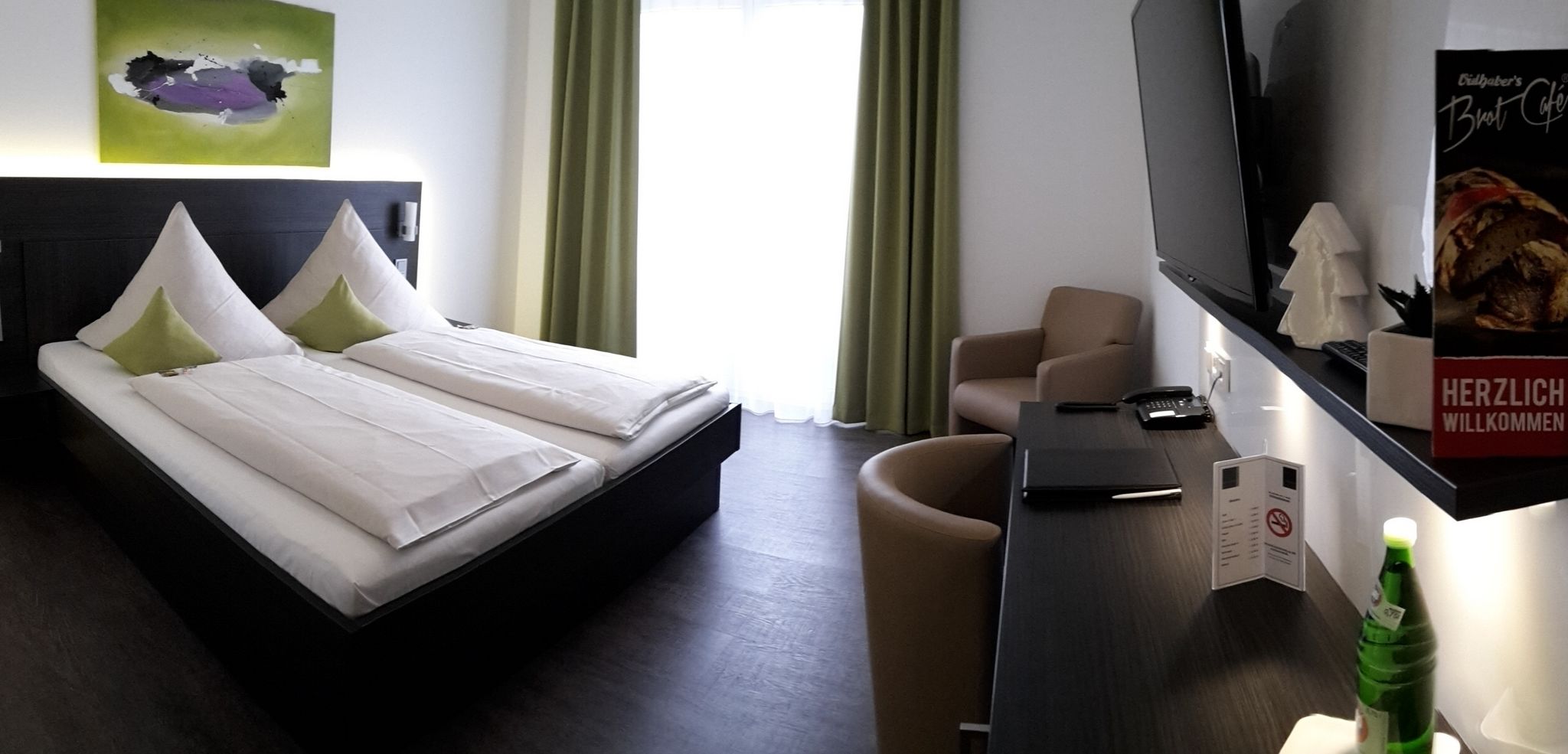 A hotel room with a bed, a desk, a chair, and a television.