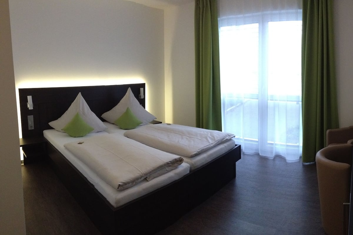 A hotel room with a bed, a desk, a television, and a window with curtains.