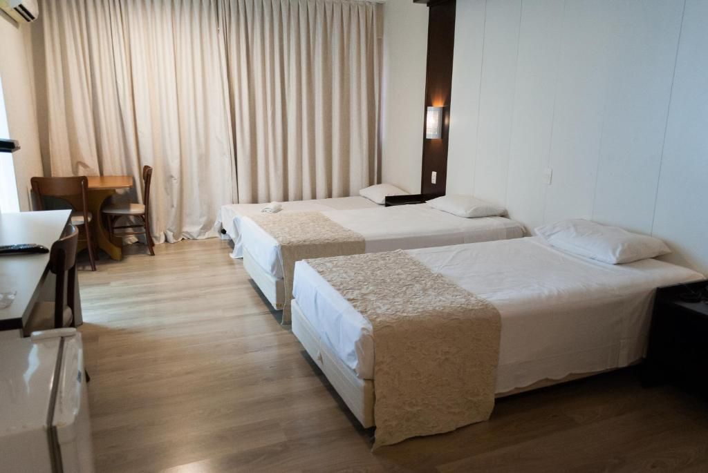 Una habitació d'hotel amb dos llits, una taula i una cadira.