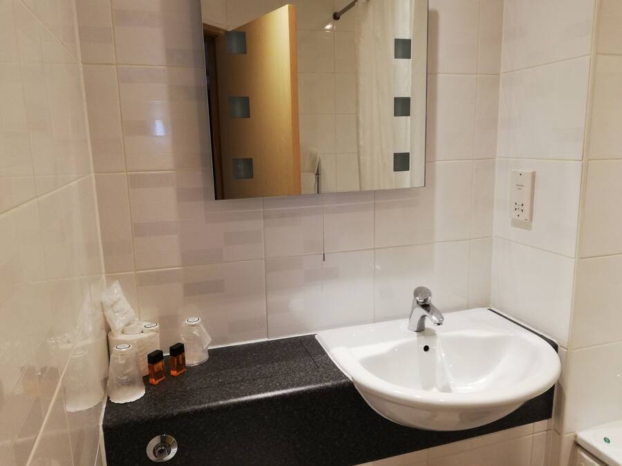 A modern bathroom with a white sink, black countertop, and tiled walls.
