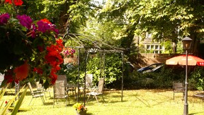 A garden with a swing set, chairs, and a table. - Haley's Hotel (Leeds)