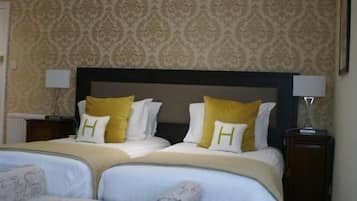 Habitación de hotel con una cama grande, dos mesitas de noche, una silla y una alfombra estampada.