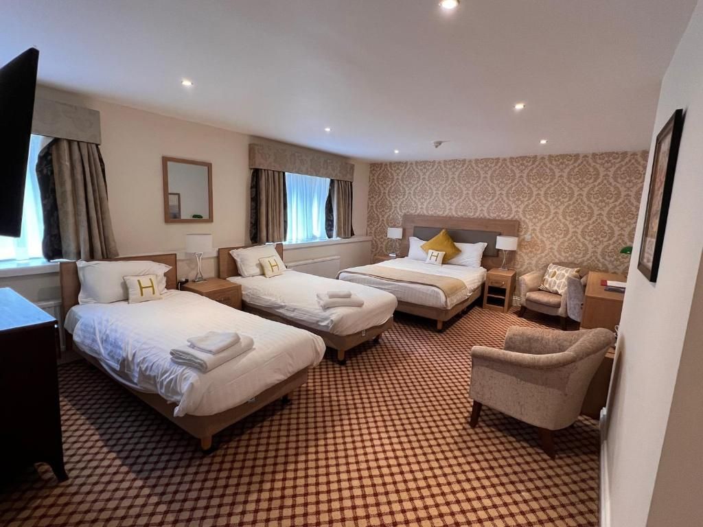 A hotel room with three beds, a chair, and a small table.