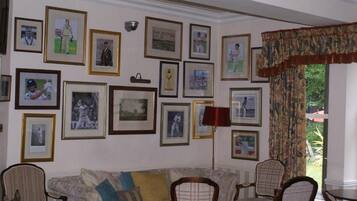 Una sala de estar con un sofá, sillas y una pared decorada con cuadros.