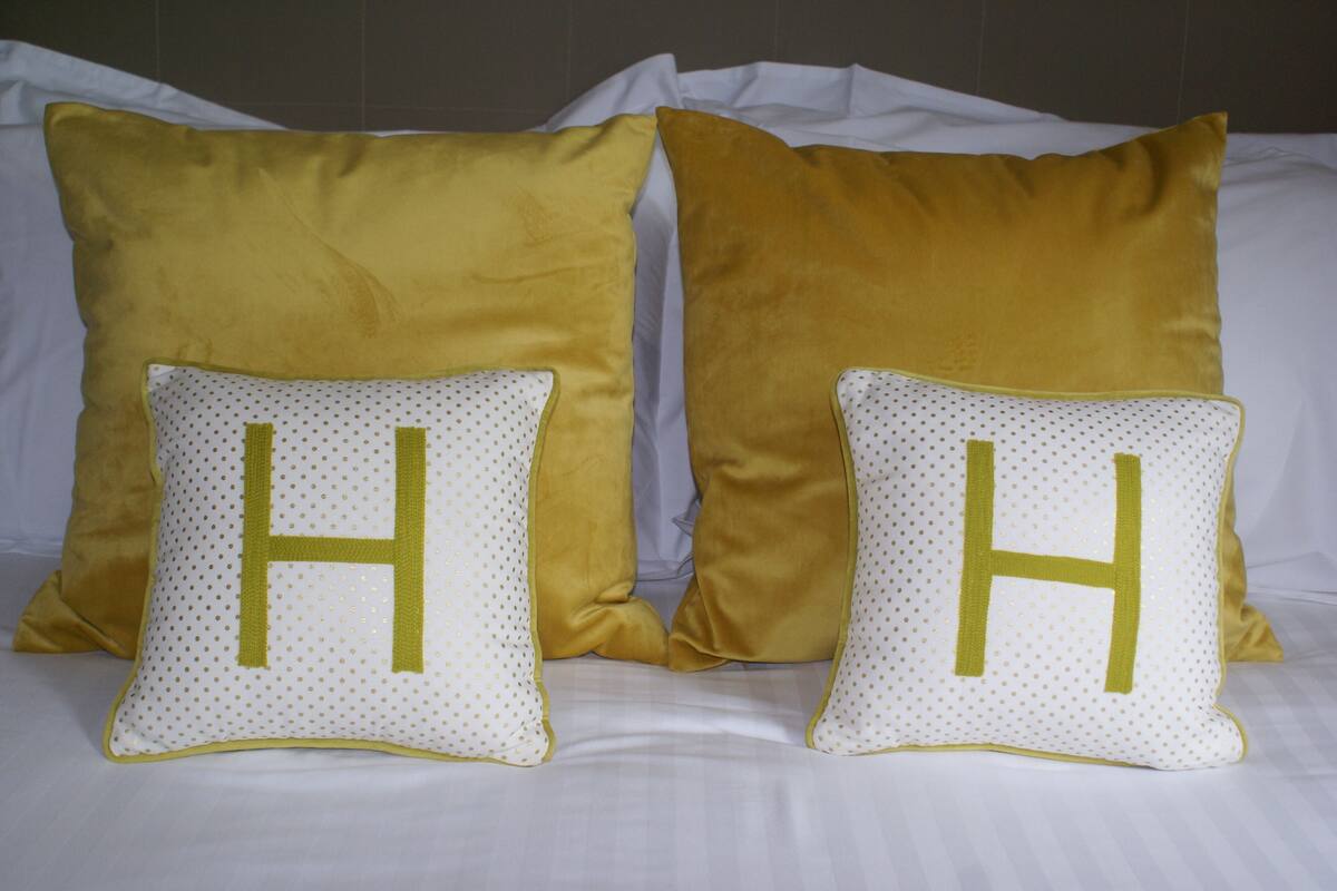 Two pillows with large 'H' letters on a bed.