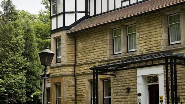 A two-story stone building with a prominent tower, a stone entrance, and a small porch with a lamp post. - Haley's Hotel (Leeds)