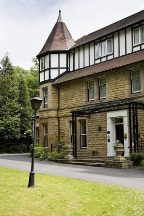 A two-story stone building with a prominent tower, a stone entrance, and a small porch with a lamp post. - Haley's Hotel (Leeds)