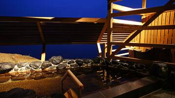 A wooden deck with a stone wall and a wooden railing.
