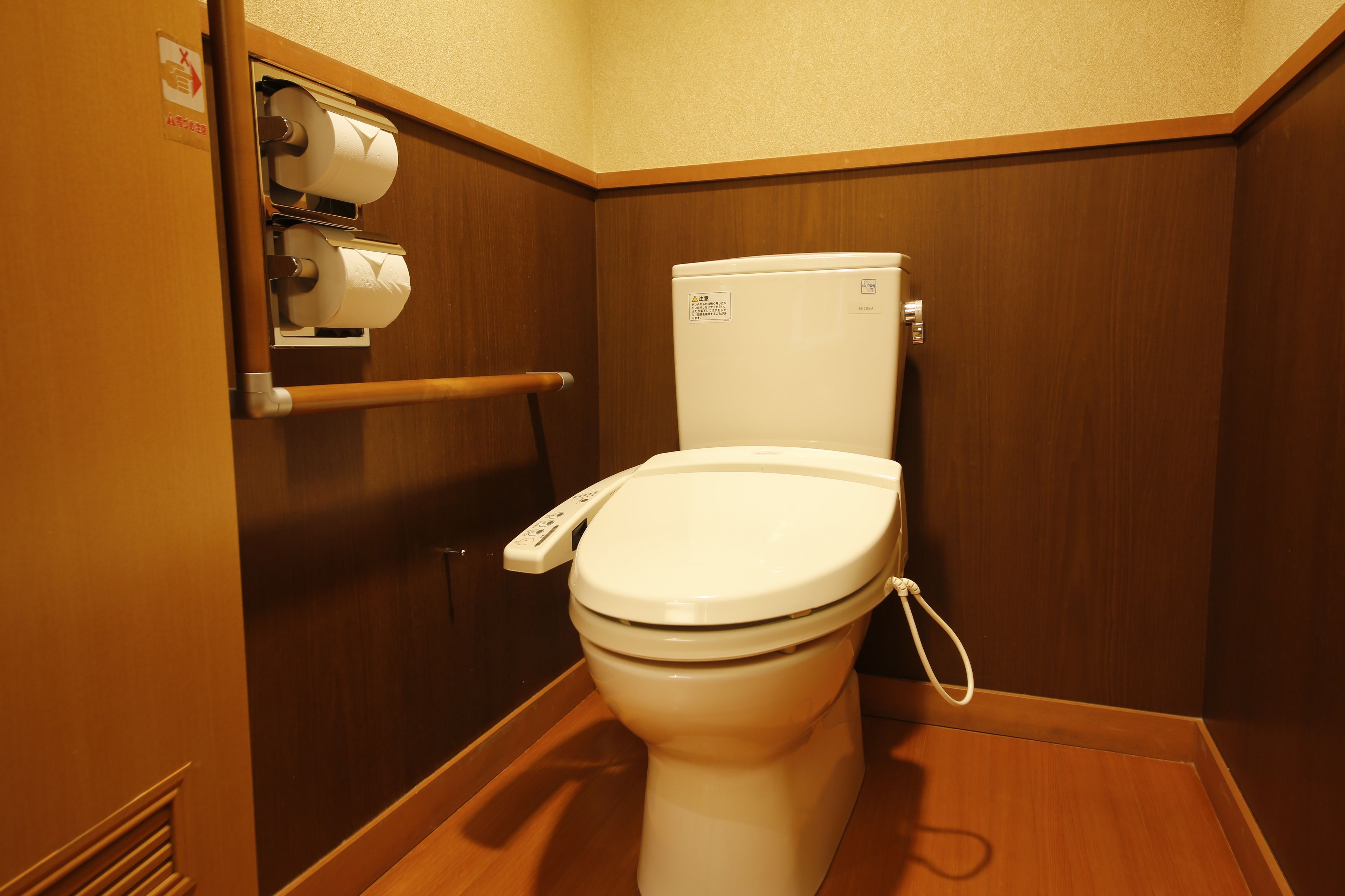 A small, compact bathroom with a white toilet, a hand dryer, and a paper towel dispenser.