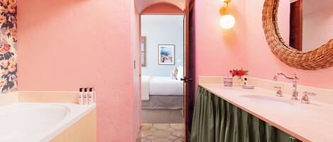 A bathroom with a bathtub, a sink, and a mirror. There is a door leading to another room.