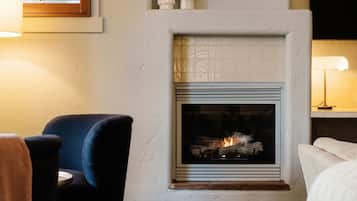 Una habitación acogedora con chimenea, un sillón cómodo y un sofá.