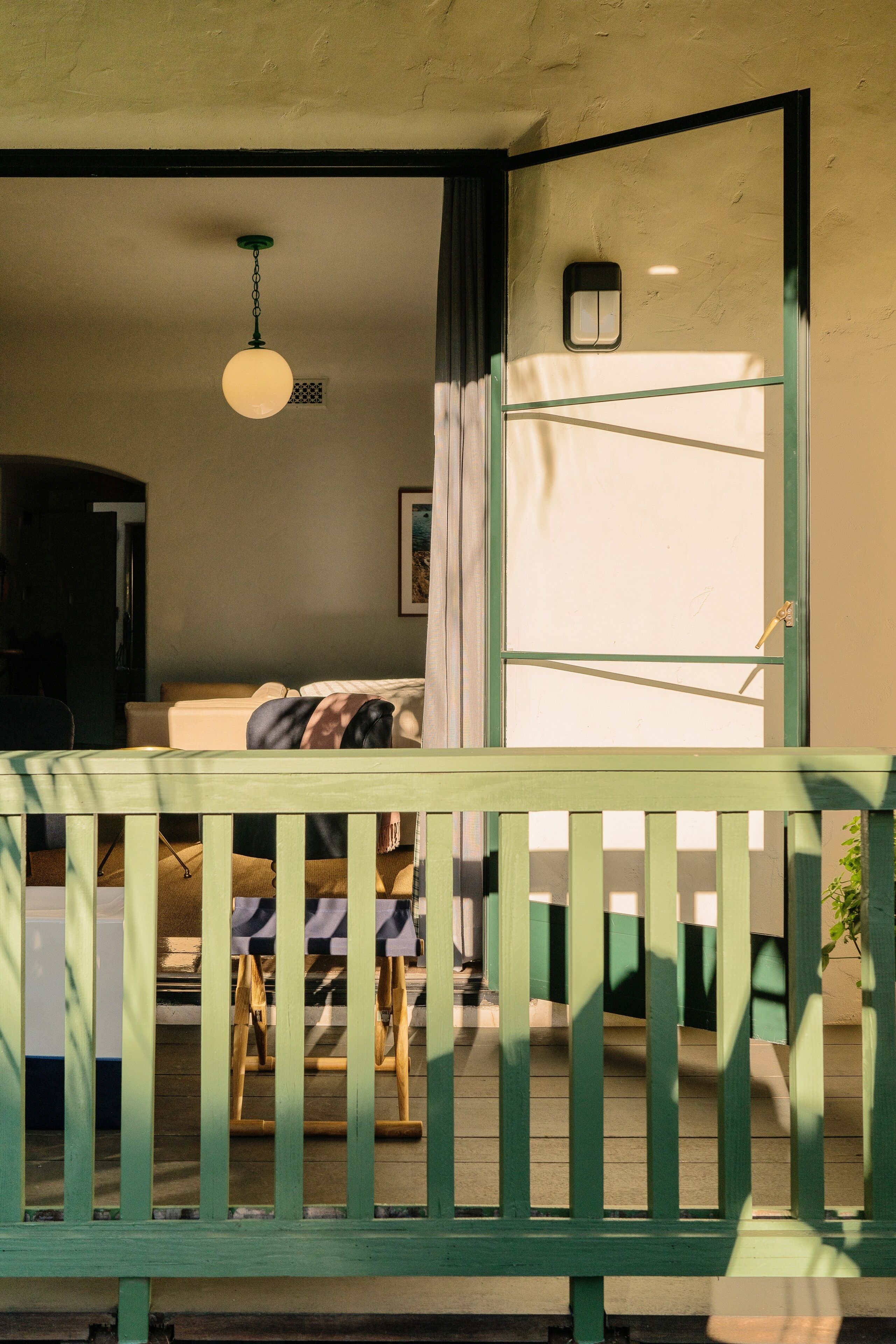 Una habitación con cama, lámpara colgante, ventana con cortinas y un banco de madera.