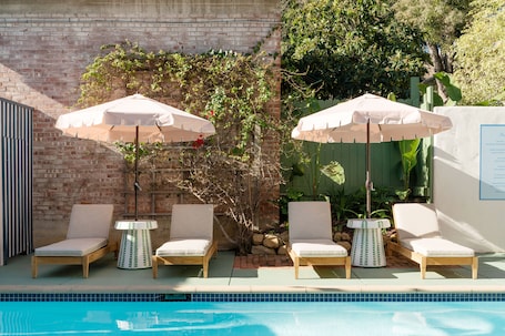 Una piscina al aire libre, sombrillas, sillones reclinables de piscina