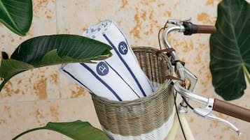 En gammal cykel med en korg av rotting som innehåller en vit duk och ett blå- och vitrandigt föremål.
