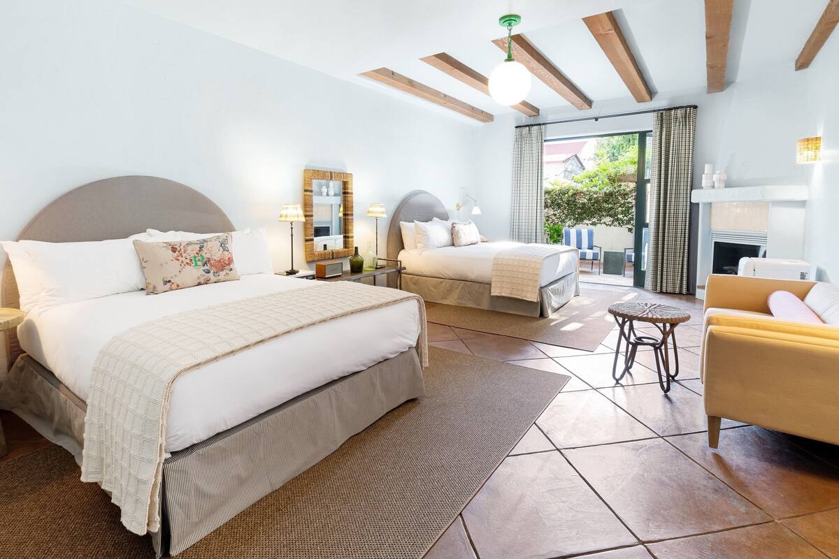 Ein Hotelzimmer mit zwei Betten, einem Sofa, einem kleinen Tisch und einem Kamin.