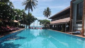 A swimming pool with tiled flooring, surrounded by lounge chairs and palm trees. - Tommy Resort (Ko Pha-ngan)