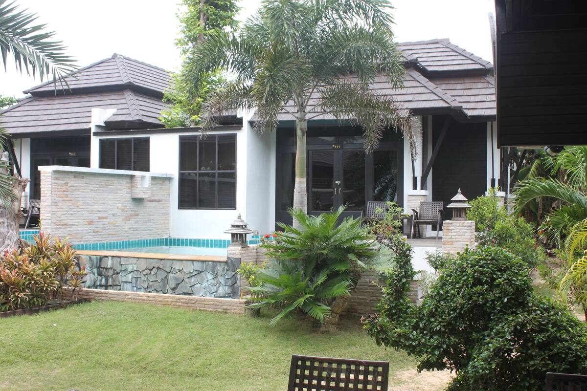 Una casa con fachada de piedra, piscina y jardín cuidado.