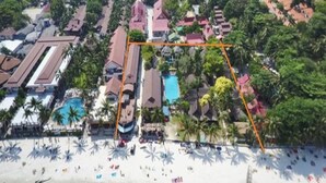 An aerial view of a resort with multiple buildings, a swimming pool, and a beach area with umbrellas. - Tommy Resort (Ko Pha-ngan)