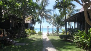 A pathway leading to a beach with palm trees and a wooden structure. - Tommy Resort (Ko Pha-ngan)