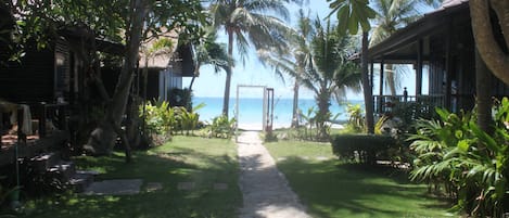 A pathway leading to a beach with palm trees and a wooden structure.