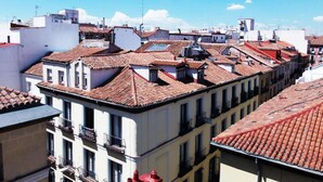 A cityscape with traditional red-tiled roofs and white buildings, featuring balconies and a clear blue sky. - Hostal Dolcevita (Madrid)