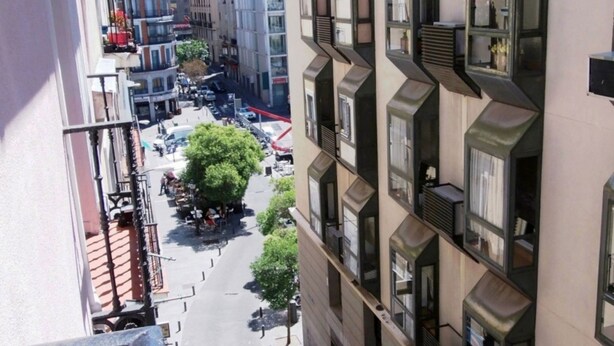 A multi-story building with balconies, large windows, and a street view below. - Hostal Dolcevita (Madrid)