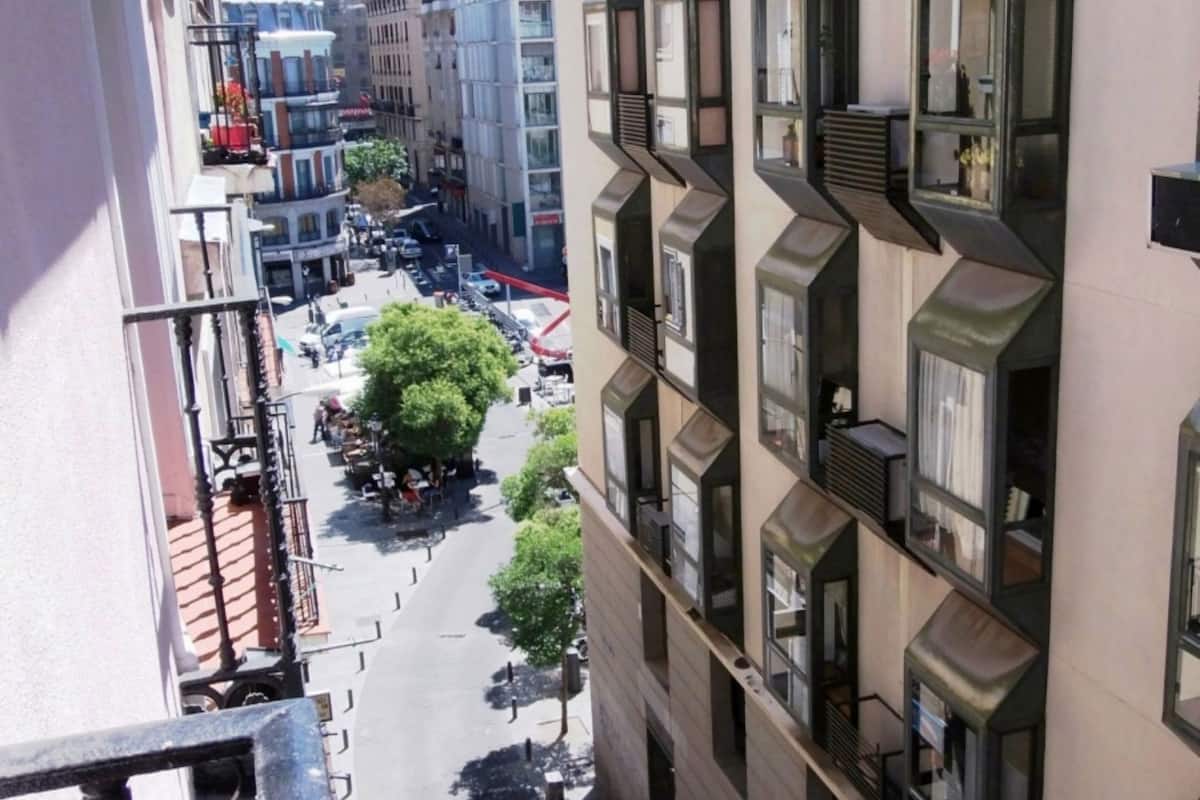 A multi-story building with balconies, large windows, and a street view below.