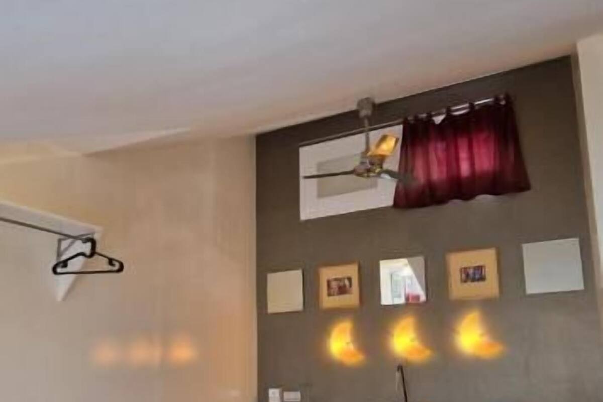 A small, cozy room with two beds, a wooden table, and a hanging light fixture.