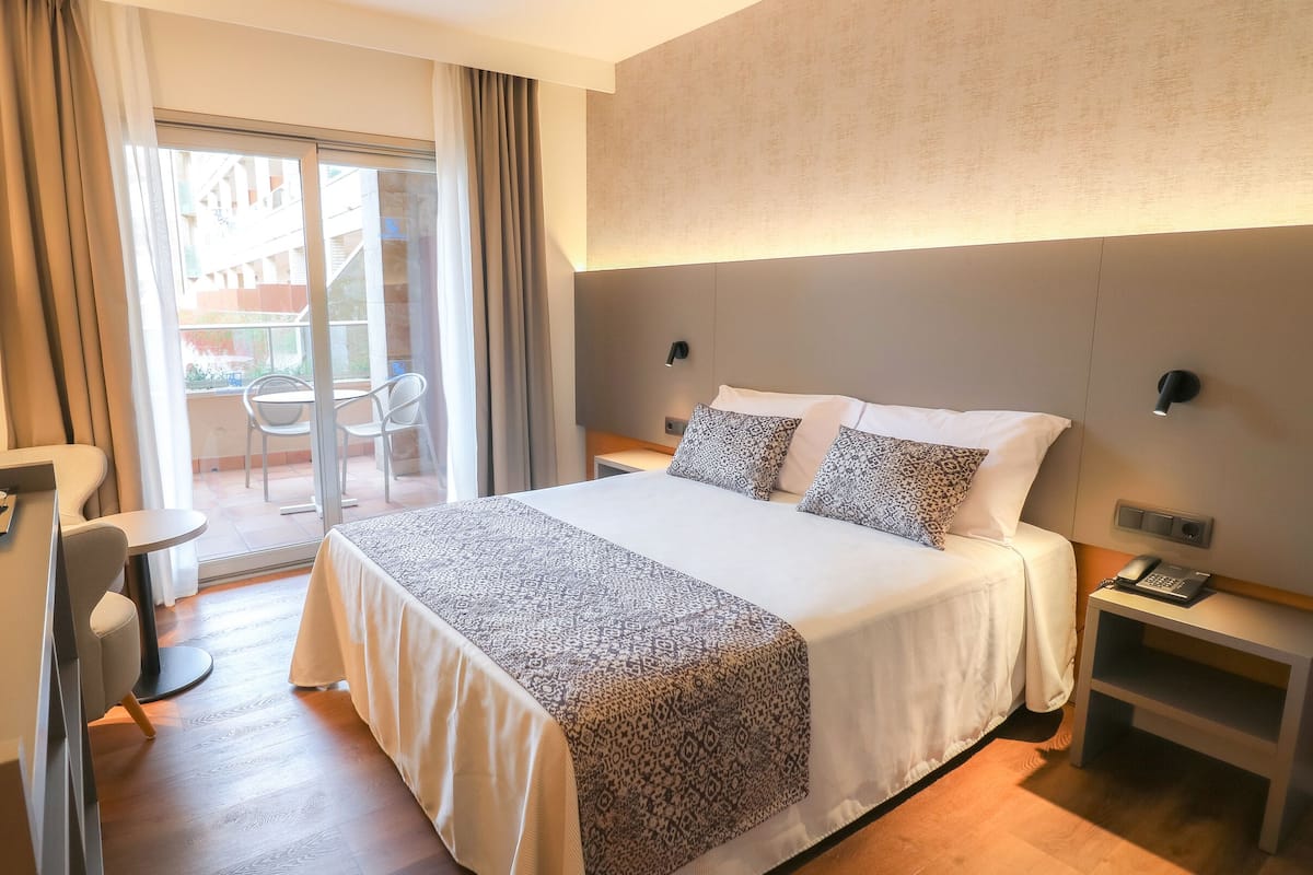 Une chambre d’hôtel avec un grand lit, un bureau avec une machine à café, un téléphone et une petite table.
