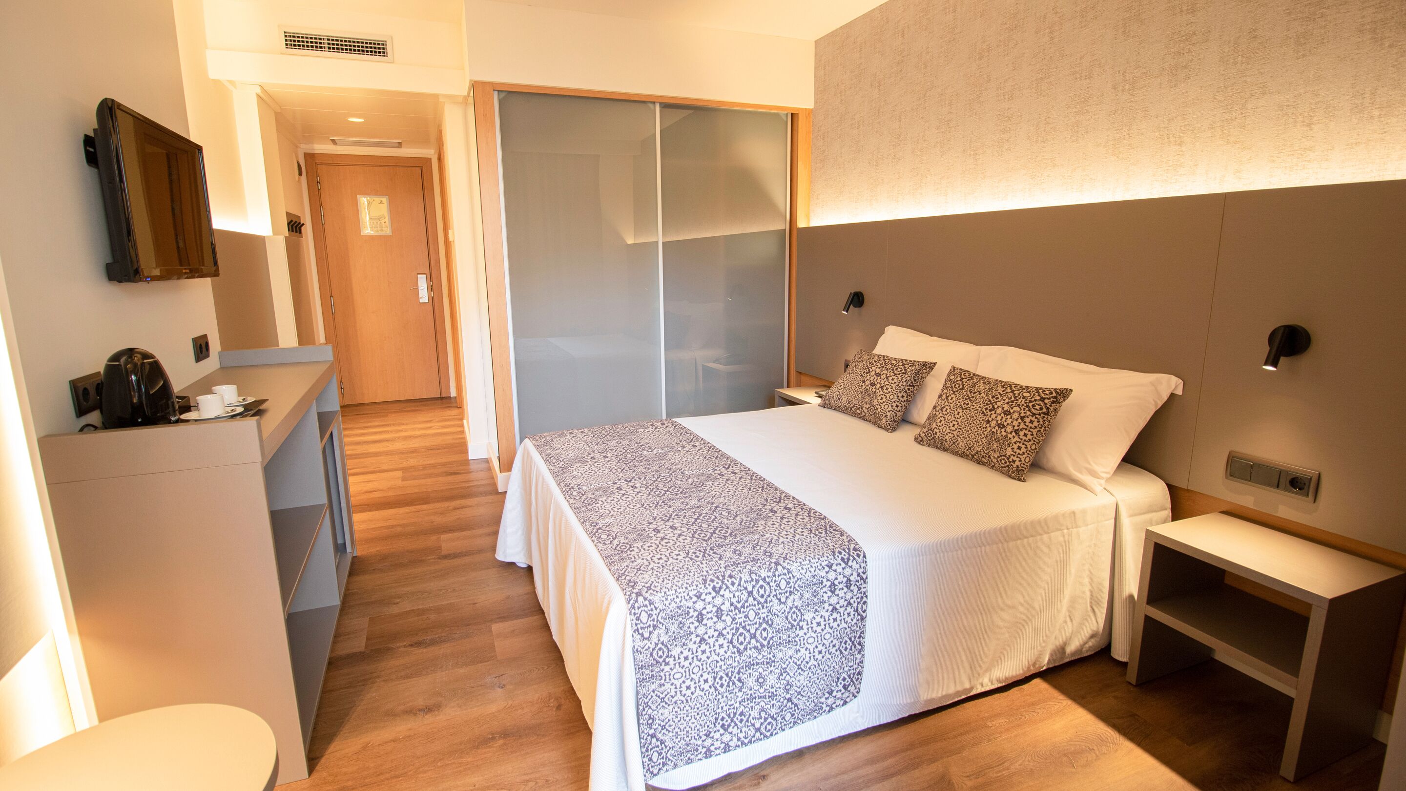 Une chambre d’hôtel équipée d’un lit, d’une table de chevet et d’un bureau avec une machine à café.