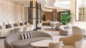 Un moderno vestíbulo de hotel con área de descanso, sofás y una planta grande en maceta.