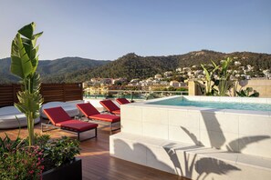 Zona de piscina en la azotea con sillones y vistas a un pueblo en la ladera.