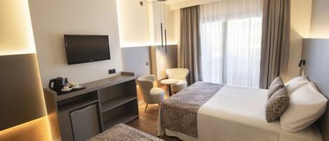 A hotel room with a bed, a desk, a chair, a television, and a window with curtains.