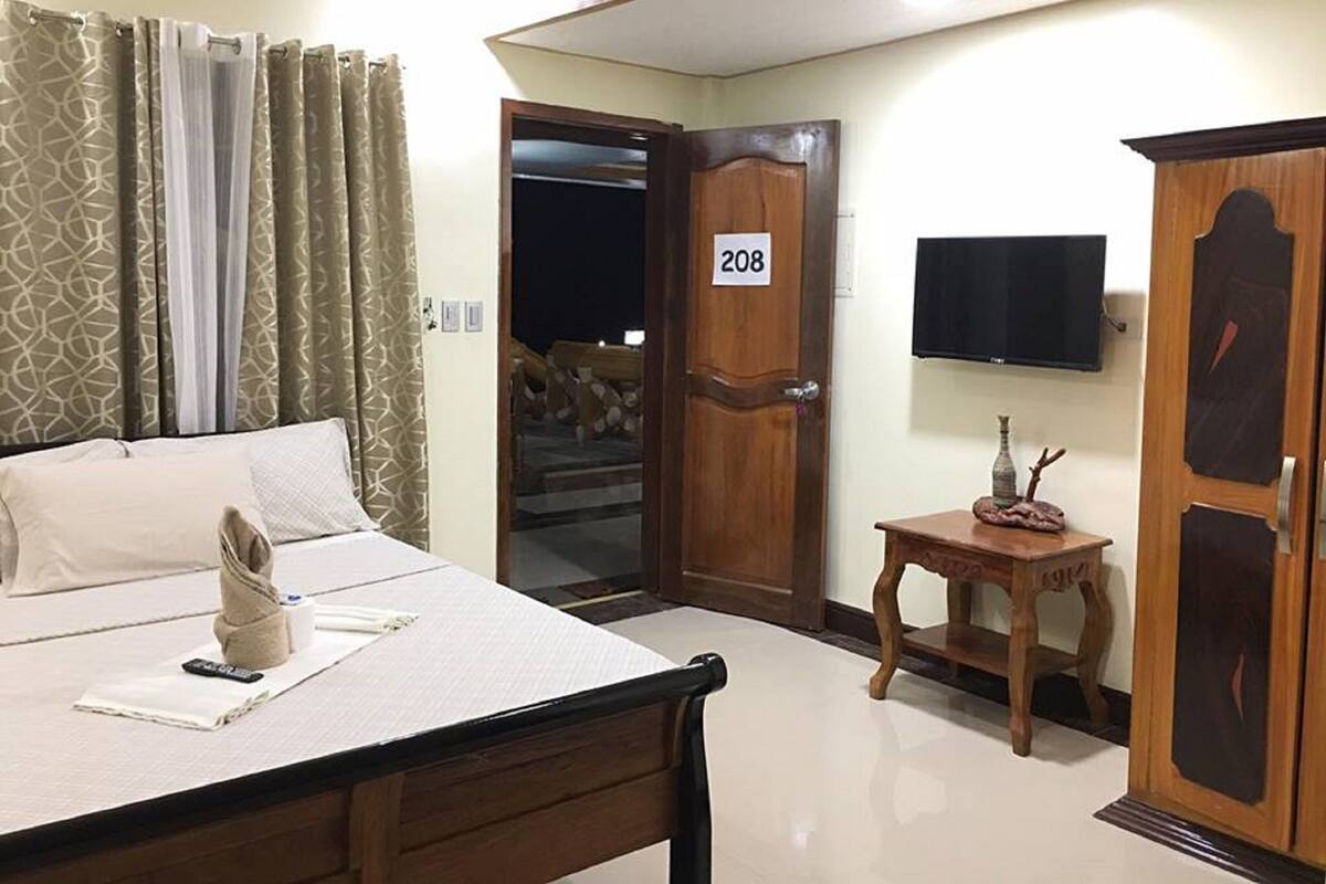 Une chambre d’hôtel avec un lit, une petite table, un téléviseur et une armoire.