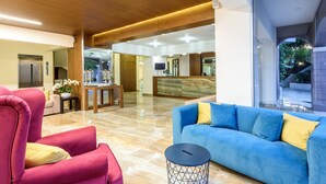 A spacious lobby with a blue sofa, a red armchair, and a small round table. - Eurohotel Katrin Hotel & Bungalows (Hersonissos)