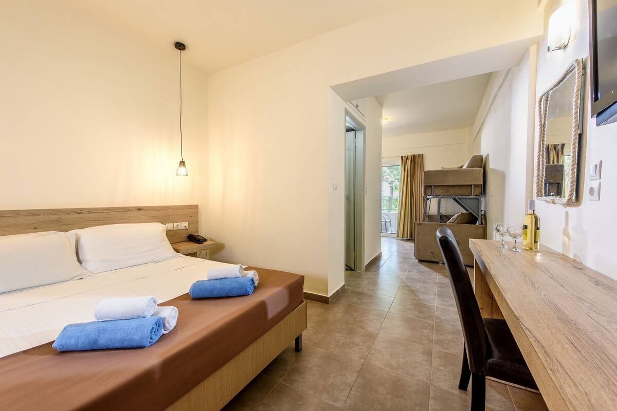 A hotel room with a bed, bedside table, and a wooden dining table with chairs.