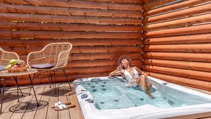 A hot tub in a wooden deck area with wicker chairs and a table with fruits. - Eurohotel Katrin Hotel & Bungalows (Hersonissos)
