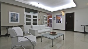 Un área de espera moderna con un sofá blanco, una mesa de centro de vidrio y un cuadro en la pared.