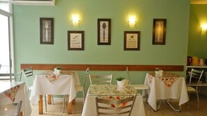 Un comedor con mesas y sillas, obras de arte enmarcadas en la pared y un banco de madera.