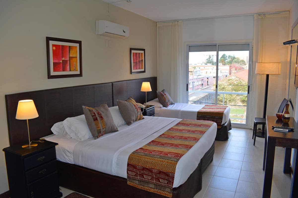 Une chambre d’hôtel avec deux lits, un bureau, une chaise et une vue sur la ville.