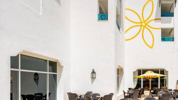 An outdoor seating area with wicker furniture and a large yellow flower design on the building.