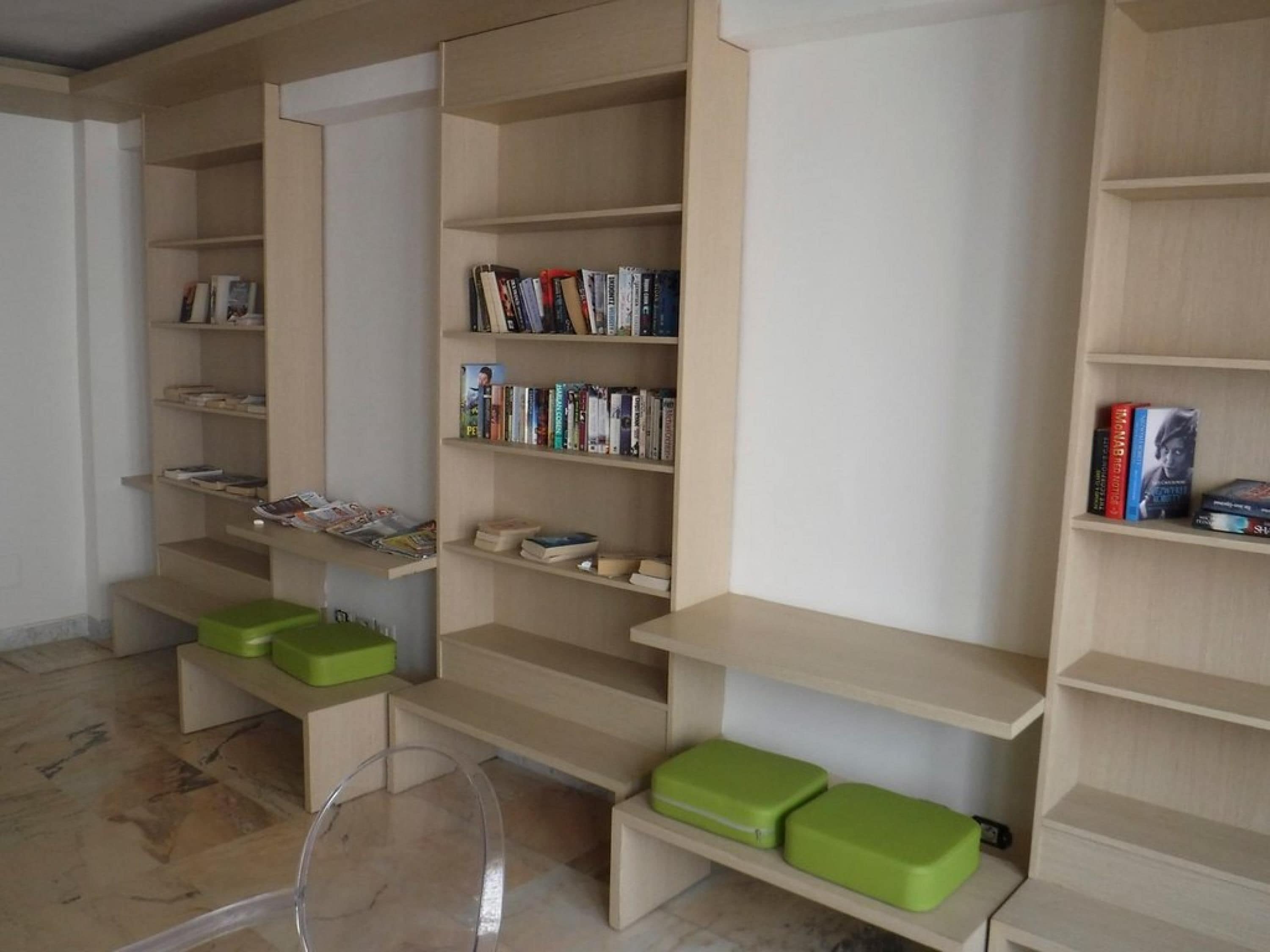 Una biblioteca con scaffali multipli e contenitori verdi.